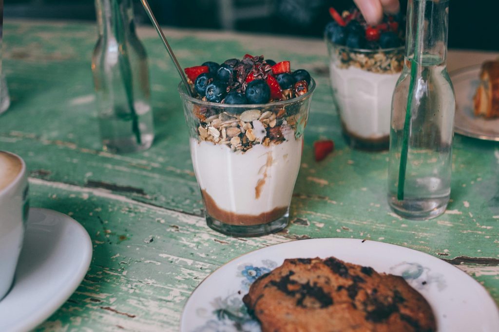 Portions of appetizing sweet dessert with oatmeal and berries in glasses on shabby wooden table